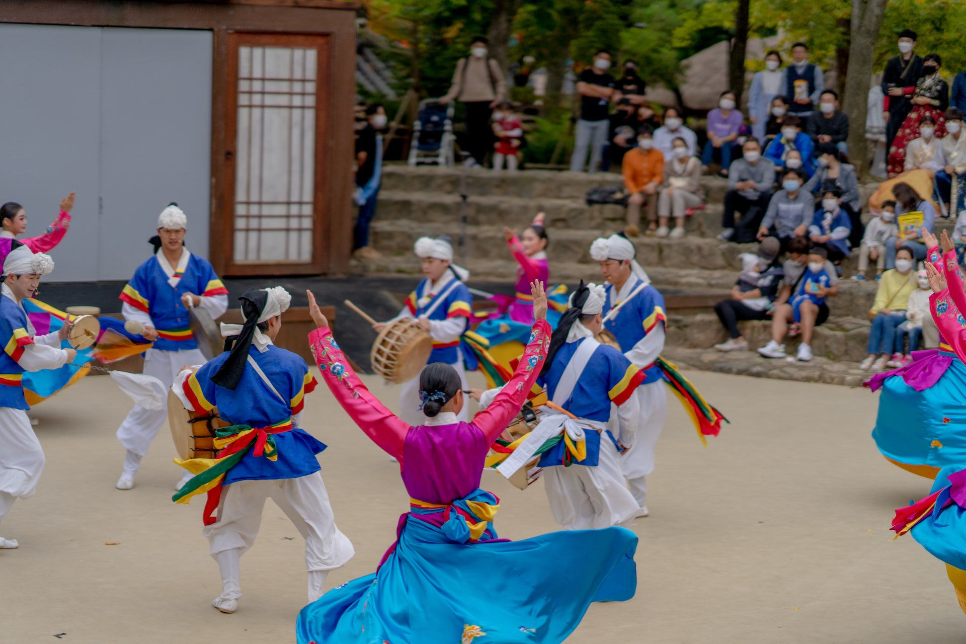 A photo of Korean folk dancers in colorful costumes performing for a crowd