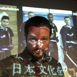 Carl Gabrielson in front of a projector showing Japanese imagery
